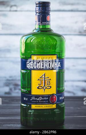 Kharkiv, Ukraine, November 15, 2019: A full glass green bottle of becherovka on gray wooden background. Strong drink - czech herbal liqueur. Illustrat Stock Photo