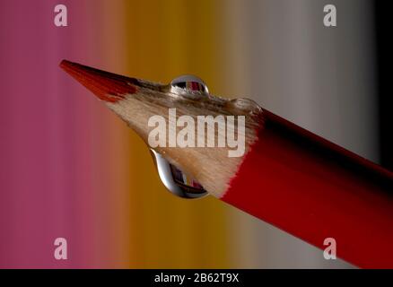 Macro of wooden crayon on colourful background with water drop Stock Photo