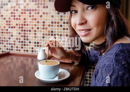 the girl drinks coffee at a roadside cafe. Warm Colors Toned Stock Photo