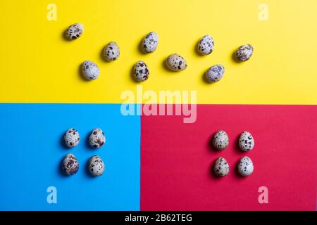 Abstraction of colorful Easter quail eggs on colorful paper. Top view with copy space. Square image Stock Photo
