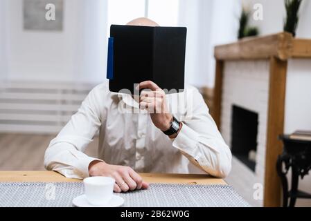 A man is reading something in a black notebook. The concept of freelance, work in the office. Stock Photo