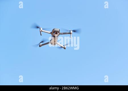 Drone With Camera Flying Against Clear Blue Sky Stock Photo