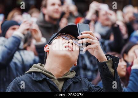 PRAGUE, CZECH REPUBLIC - 18 MARCH, 2017: Surprised Asian man and large crowd of tourists photograph on smartphones and look up at the city's landmark Stock Photo