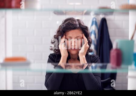 View Through Bathroom Cabinet Of Mature Woman With Headache Stock Photo
