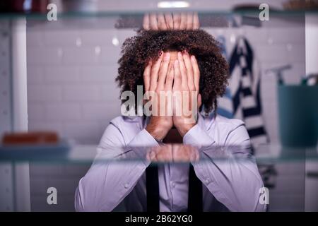 View Through Bathroom Cabinet Of Unhappy Businessman Covering Face With Hands Stock Photo