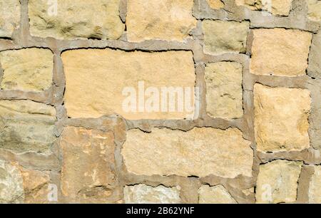 background texture-close up of vintage pastel sandstone block wall with grout Stock Photo