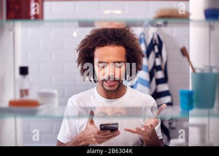 View Through Bathroom Cabinet Of Businessman Using Mobile Phone To Practise Presentation Stock Photo