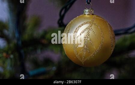 Golden bauble with leaf pattern hanging on a Christmas tree Stock Photo