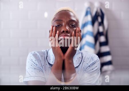 View Through Bathroom Cabinet Of Unhappy Young Woman Getting Ready For Work Stock Photo
