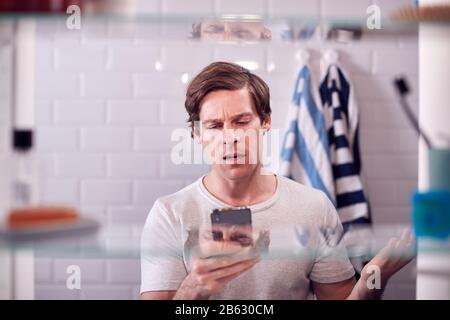 View Through Bathroom Cabinet Of Businessman Using Mobile Phone To Practise Presentation Stock Photo