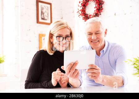 Shot of a mature couple using a digital tablet while sitting at desk at home. Stock Photo