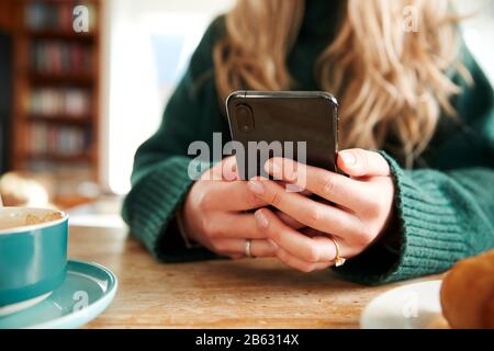 Close Up Of Woman Using Mobile Phone Sitting At Table  In Cafe Stock Photo