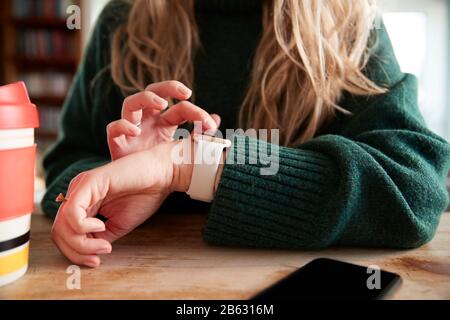 Close Up Of Woman Using Smart Watch Sitting At Table  In Cafe Stock Photo