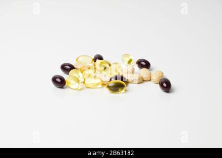Scattered pills on a white background. Astaxanthin, fish oil and vitamins. Stock Photo
