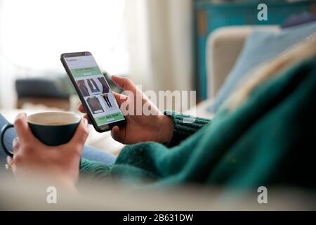Close Up Of Woman Shopping For Clothes Online Using Mobile Phone App Stock Photo