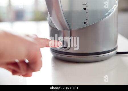 Close Up Of Woman Pressing Power Switch On Electric Kettle To Save Energy At Home Stock Photo