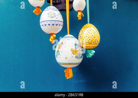 Pretty Colored Easter Eggs hanging on Ribbons decorated with bows on blue background Stock Photo