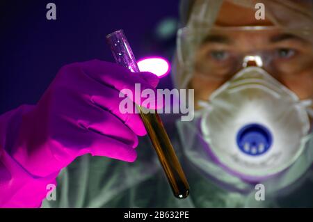 Scientist in mask and protection glass with test-tube in glove hand. Concept of laboratory, science research, biology, chemistry experiment, biotechno Stock Photo