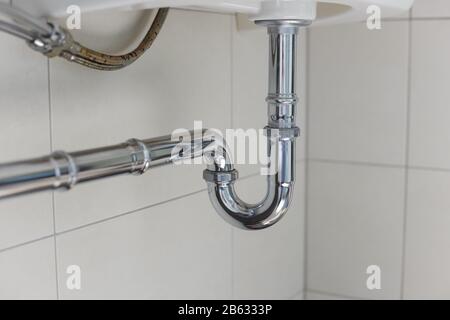 metal sink siphon and drain in white bathroom Stock Photo