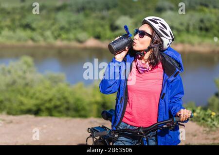 Sport young woman drinking water after doing some bicycle exercise Stock Photo