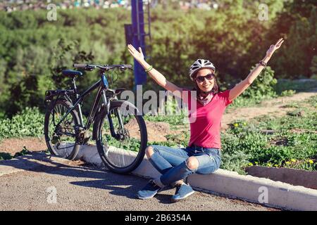 Success, achievement, accomplishment and winning concept with cyclist mountain biking. Woman cycling reaching goal raising arms at sunset cheering. Stock Photo