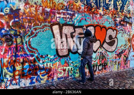 Vandal Young man Spraying paint on a Graffiti wall Stock Photo