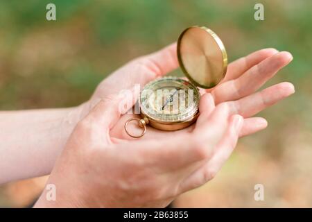 Female hiker using compass for navigation and orientation while trekking in forest, close up of hands with instrument, selective focus Stock Photo