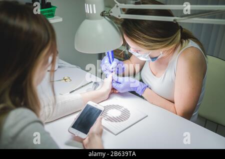 Beauty salon. Professional manicure procedure. Smartphone in hands of client Stock Photo