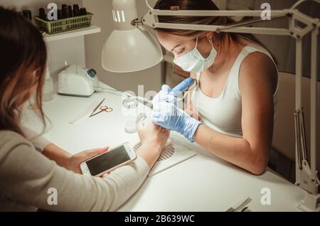 Beauty salon. Manicure procedure. Smartphone in hands of client Stock Photo