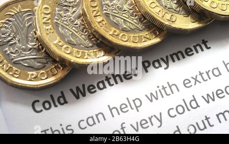 COLD WEATHER PAYMENT LEAFLET WITH ONE POUND COINS RE WINTER FUEL PENSIONS RETIREMENT PENSIONERS WINTER  ETC UK Stock Photo