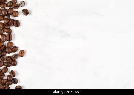 Fresh french vanilla coffee beans scattered on a white marble background with plenty of room for copy. Stock Photo