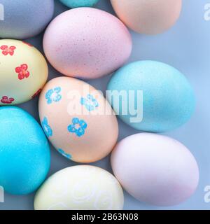 Colorful Easter eggs dyed by colored water with beautiful pattern on a pale blue background, design concept of holiday activity, top view, copy space. Stock Photo