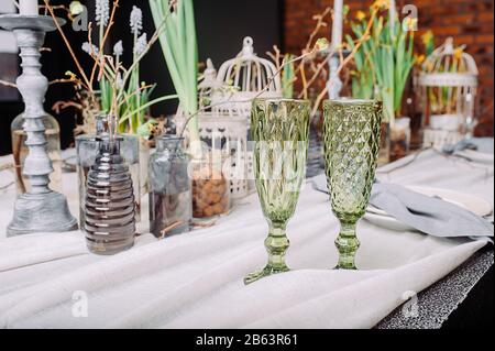 Two green drinks glasses on an eco-friendly serving table for a romantic date.Table setting in a mysterious spring style with live plants and branches Stock Photo