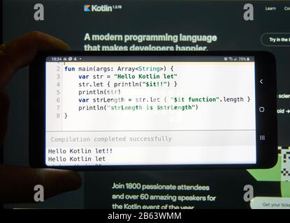 Kotlin code example on a mobile phone screen. Kotlin is a modern popular cross-platform, statically typed, general-purpose programming language Stock Photo