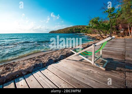 Terrace view of sea waves and coast landscape seascape rock with bench chair beach on wooden balcony / Tropical island with ocean blue sky and resort Stock Photo