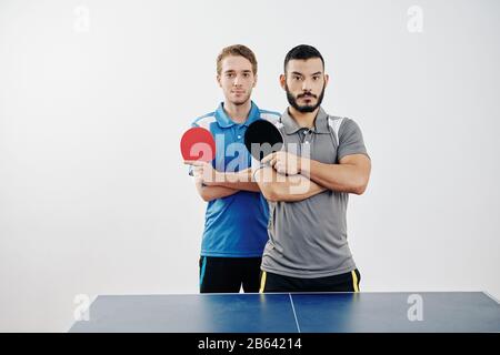 Portrait of multi-ethnic team of table tennis players in uniform posing with rackets Stock Photo