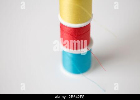 closeup blue, red, and yellow sewing thread on white background Stock Photo