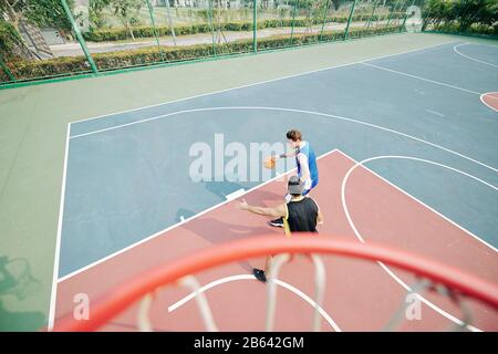 University students playing basketball on outdoor court Stock Photo