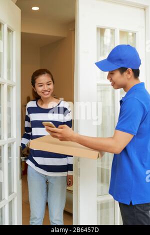 Mobile delivery servce representative in blue uniform bringing package to young woman Stock Photo