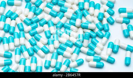 Blue and white capsule pills on white background. Pharmaceutical industry. Blue pastel color capsule pills spread on white table. Pharmaceutics. Stock Photo