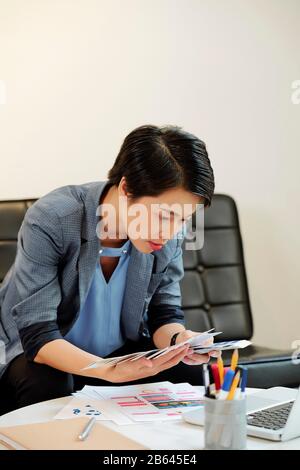 Female Vietnamese UI designer seaching for the perfect color in palette of samples Stock Photo