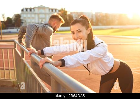 Couple in sportswear doing warm-up at the stadium Stock Photo