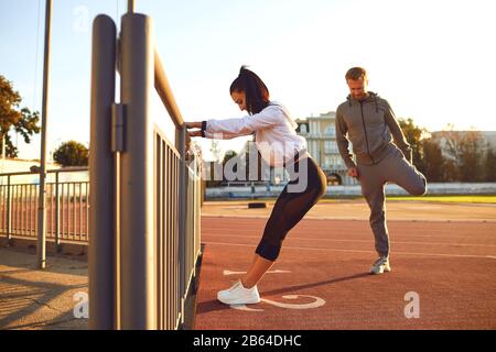 Couple in sportswear doing warm-up at the stadium Stock Photo