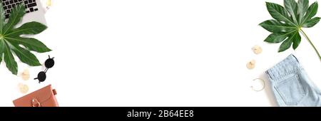 Frame made of green leaves, laptop, clothes and accessories. Summer concept banner with place for text. Stock Photo