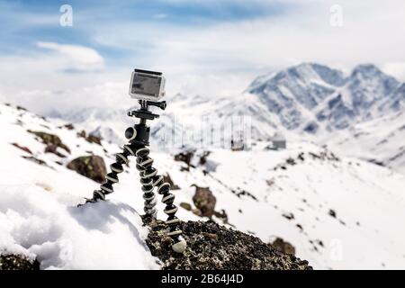Action camera mounted on a tripod gorilla with snow-capped mountains in the background Stock Photo