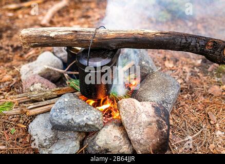 Camping kettle over burning campfire Stock Photo - Alamy