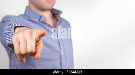 Banner with unrecognizable young businessman in blue shirt points his finger at you and touching screen. Small business concept. Teatcher pointing to Stock Photo