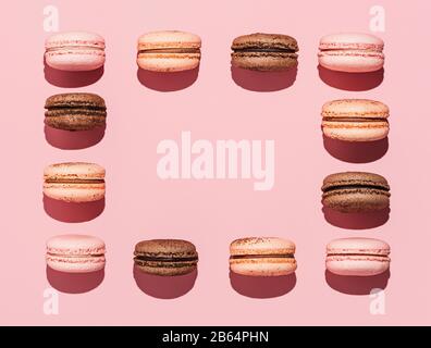 Frame made with macarons, copy space in center. Perfect french macarons or macaroons on pink background. Top view or flat lay. Hard light Stock Photo