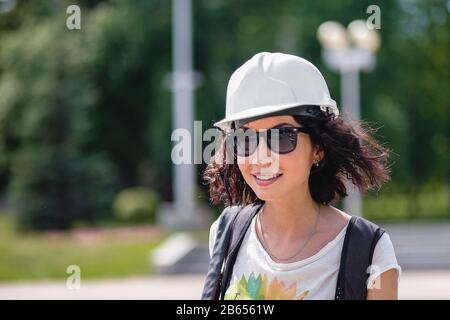 a woman in the construction helmet with sunglasses smiling Stock Photo