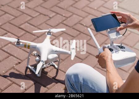 Operator holding remote control and quadrocopter. Unmanned aerial copter starting in forest. Aeromodelling, hobby, leisure concept Stock Photo